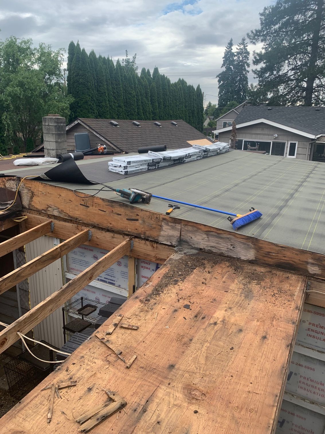A broom is sitting on top of a wooden roof.