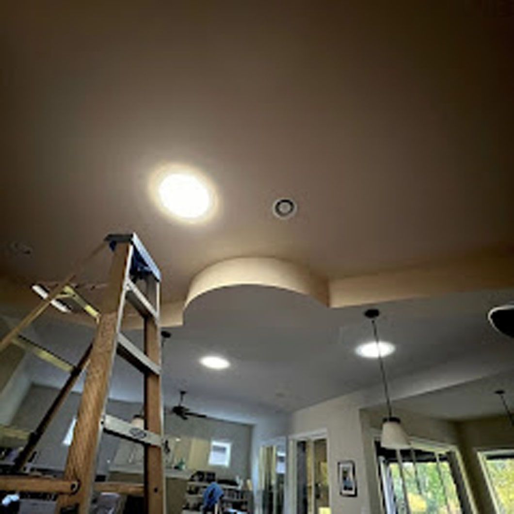 A ladder is sitting on top of a ceiling in a living room.