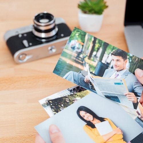 A person is holding two pictures of a man and a woman in front of a camera.