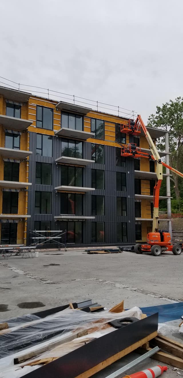 Construction d'un immeuble à plusieurs étages avec nacelle élévatrice sur site. L'extérieur du bâtiment est partiellement terminé.