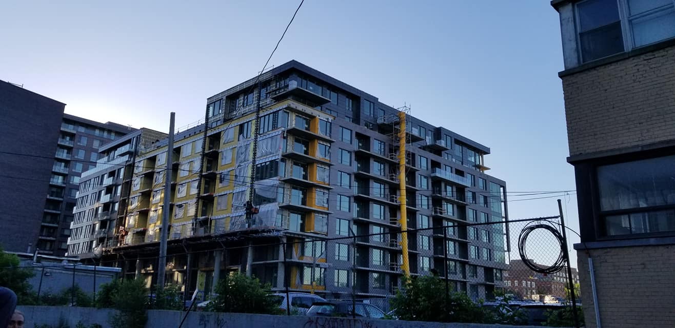 Immeubles d'appartements modernes en construction contre un ciel bleu, avec quelques matériaux de construction visibles.