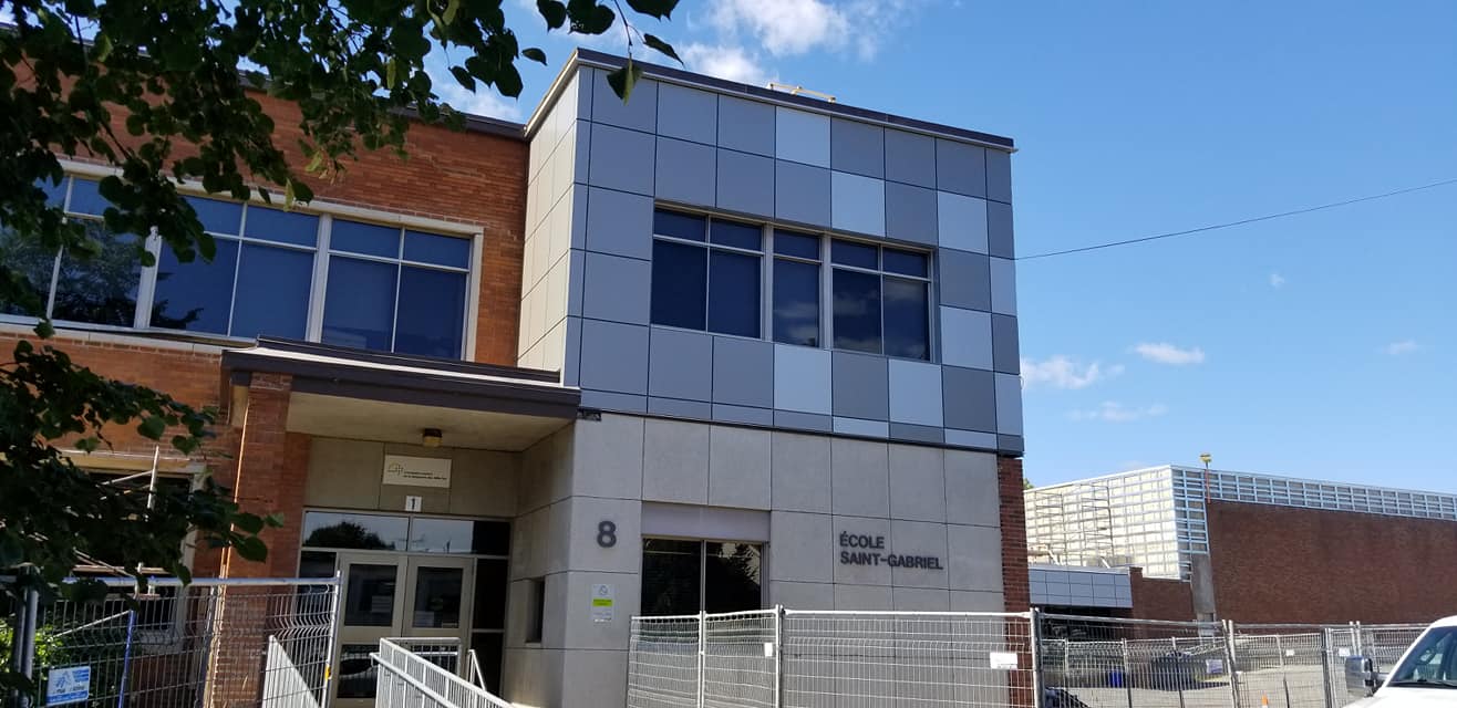 Bâtiment en briques et panneaux métalliques carrés par une journée ensoleillée.
