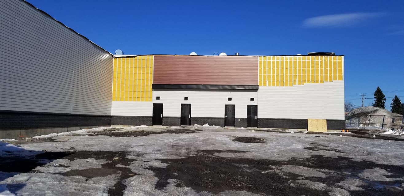 Extérieur d'un bâtiment en construction, isolation jaune et ciel bleu.