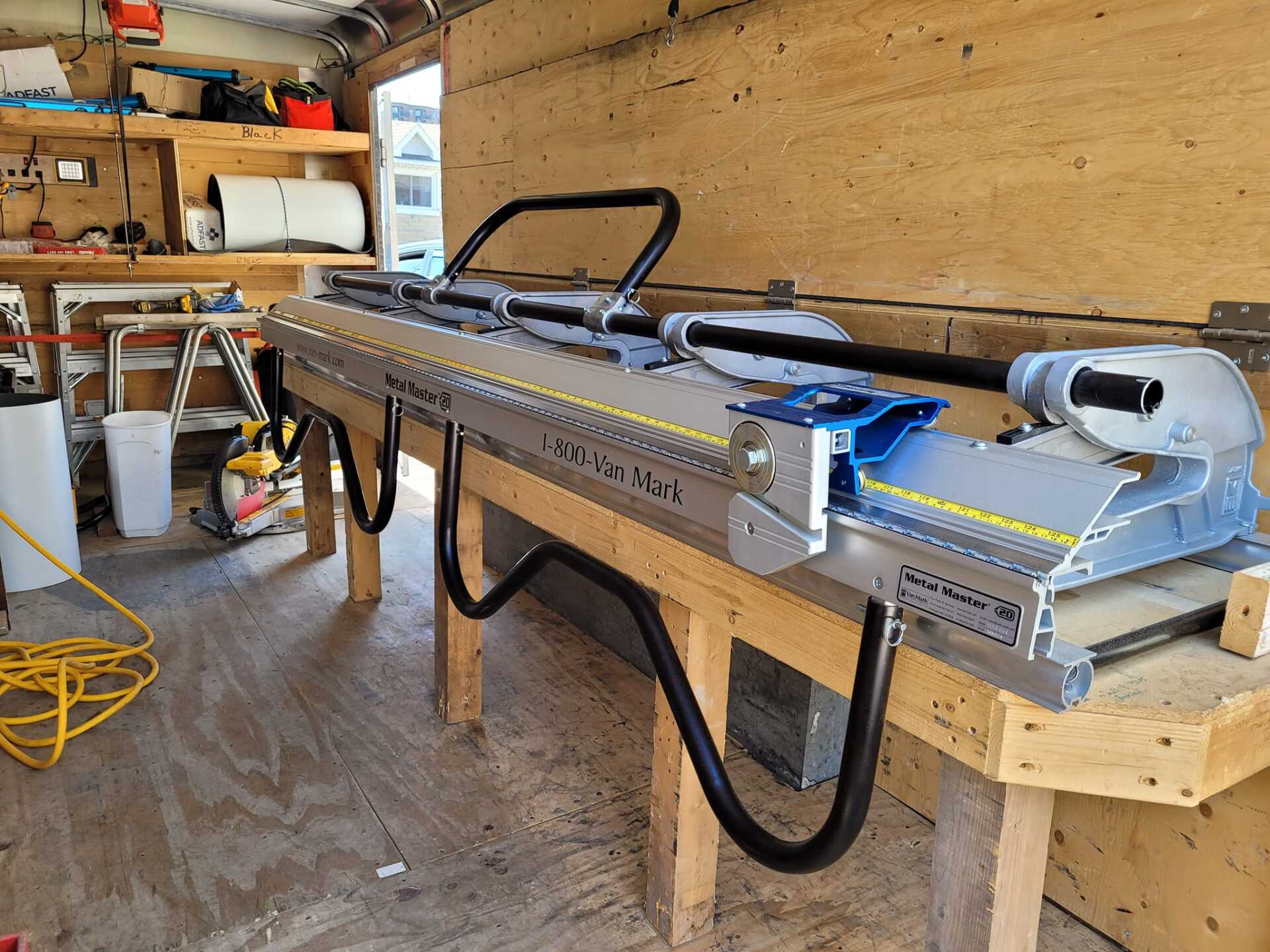 Machine à cintrer les métaux sur un établi en bois à l'intérieur d'une remorque d'atelier.