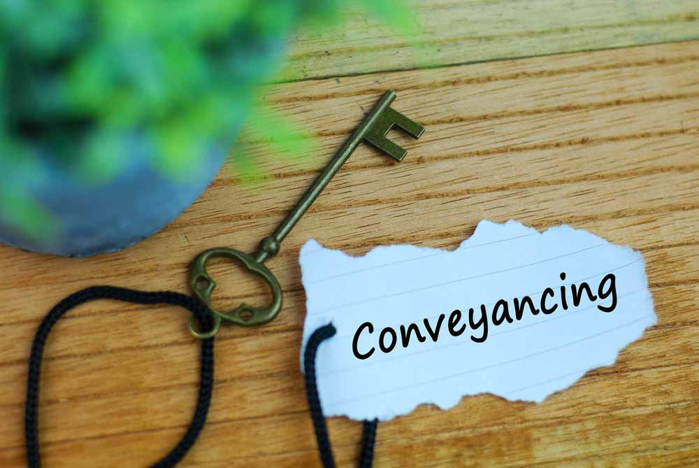 Key And Torn Paper With Text Conveyancing On Wooden Background