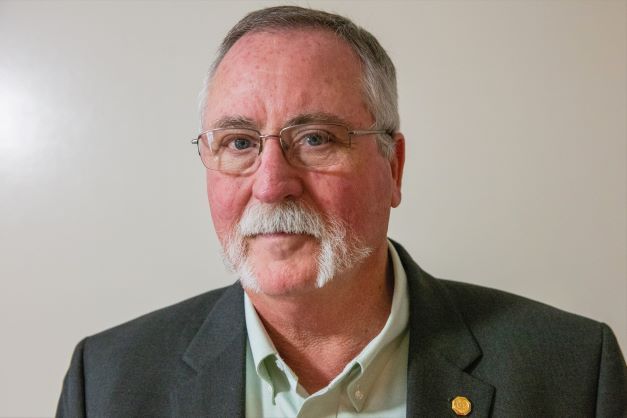 A man with glasses and a beard is wearing a suit