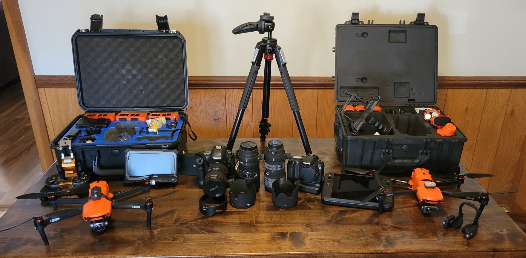 A table with cameras , drones , and a tripod on it