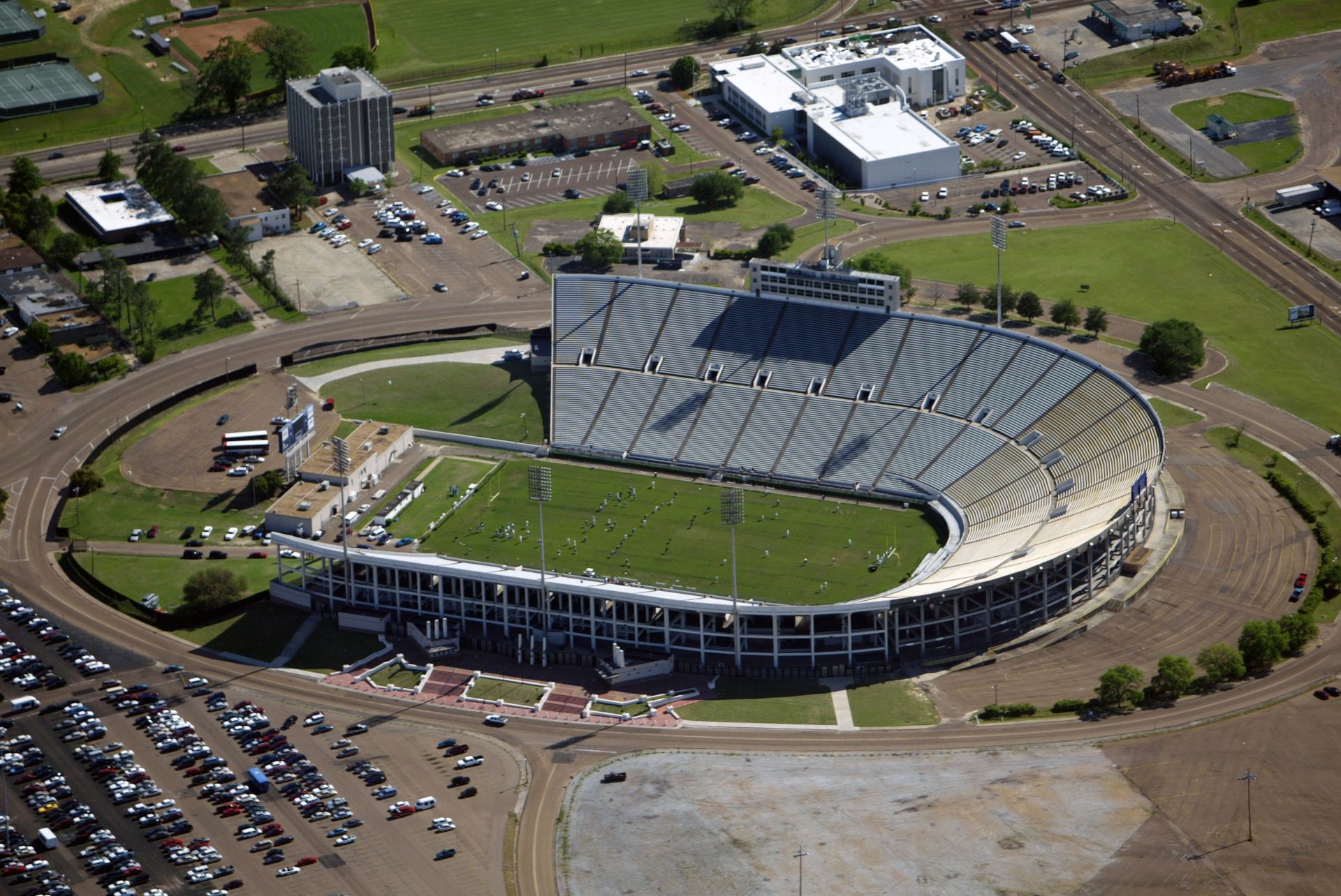 An aerial view of a stadium with a lot of cars parked in front of it