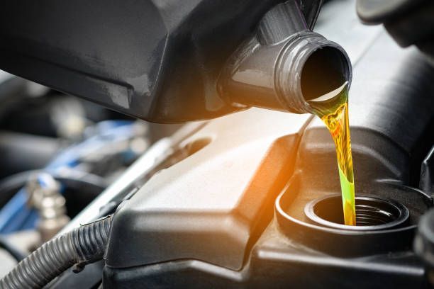 A person is pouring oil into a car engine.