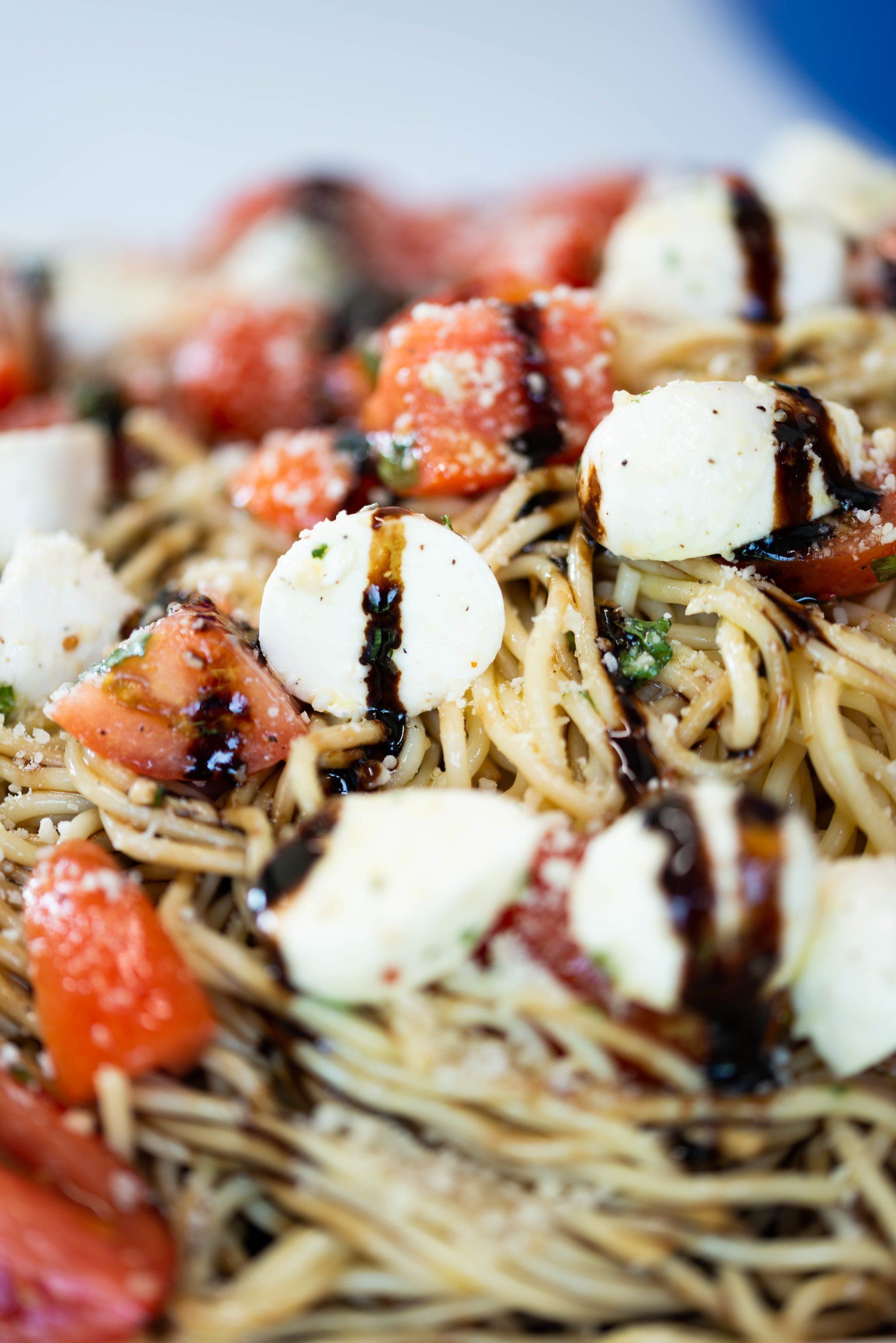 Spaghetti with fresh mozzarella balls, sliced tomatoes, and a balsamic vinaigrette drizzle.