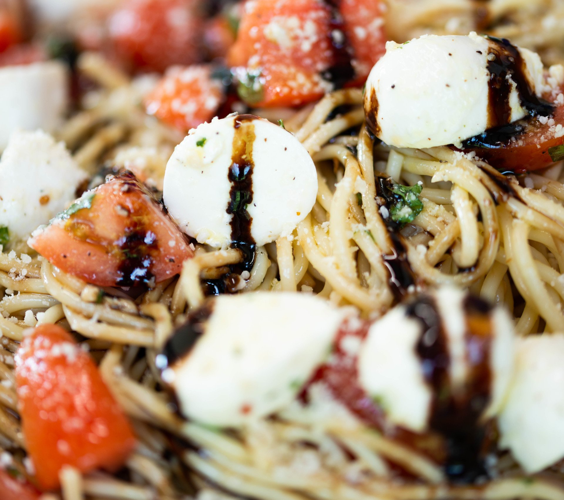 Spaghetti with fresh mozzarella balls, sliced tomatoes, and a balsamic vinaigrette drizzle.