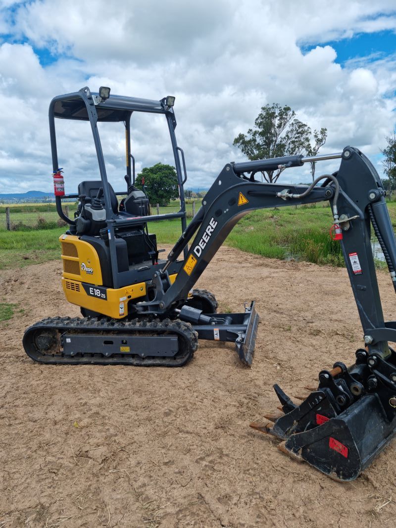 A Small Excavator is Parked in a Dirt Field — Beaudesert Equipment Hire Services in Beaudesert, QLD