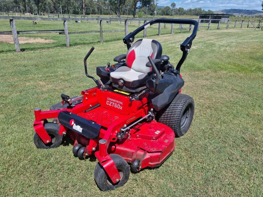 A red and black tractor is parked in a grassy field. — Beaudesert Equipment Hire Services in Beaudesert, QLD