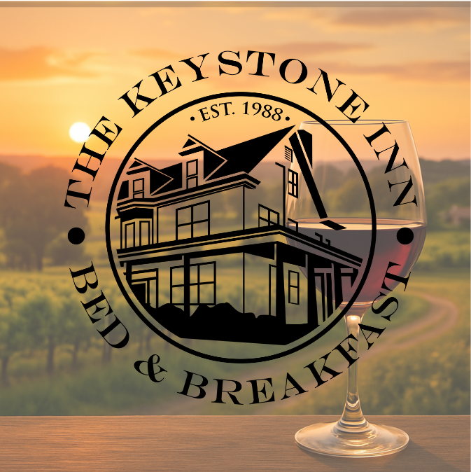 Logo for The Keystone Inn Bed & Breakfast, featuring a house illustration and wine glass over a vineyard sunset background.