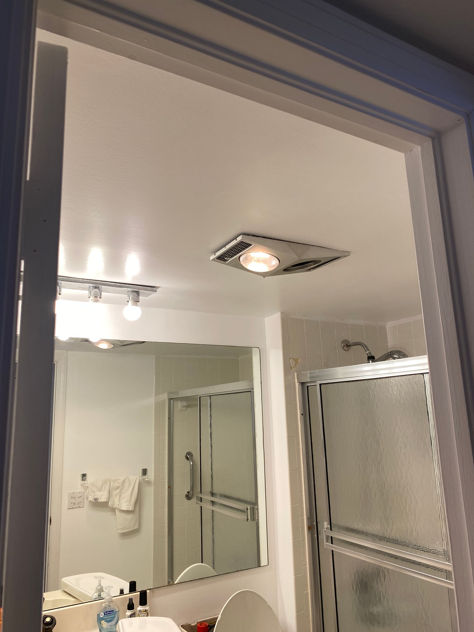 A bathroom with a large mirror and a shower stall