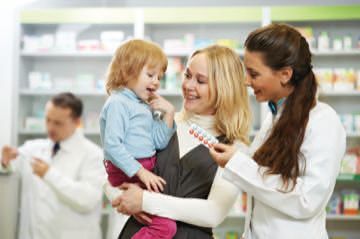 A woman is holding a little girl in her arms in a pharmacy.