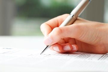 A person is writing on a piece of paper with a pen.