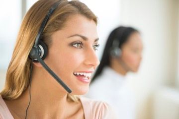 A woman wearing a headset is smiling in a call center.