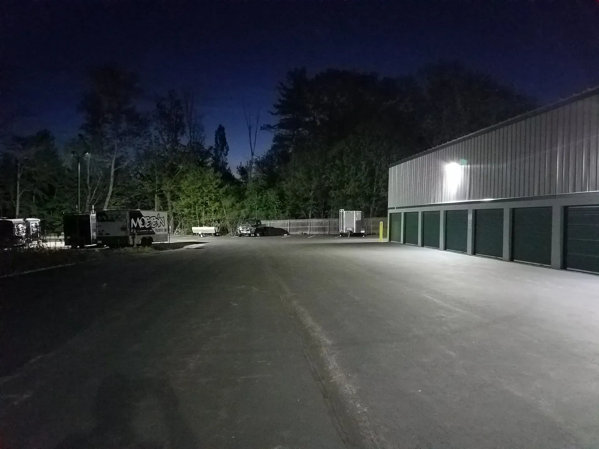 A parking lot with a building in the background at night.