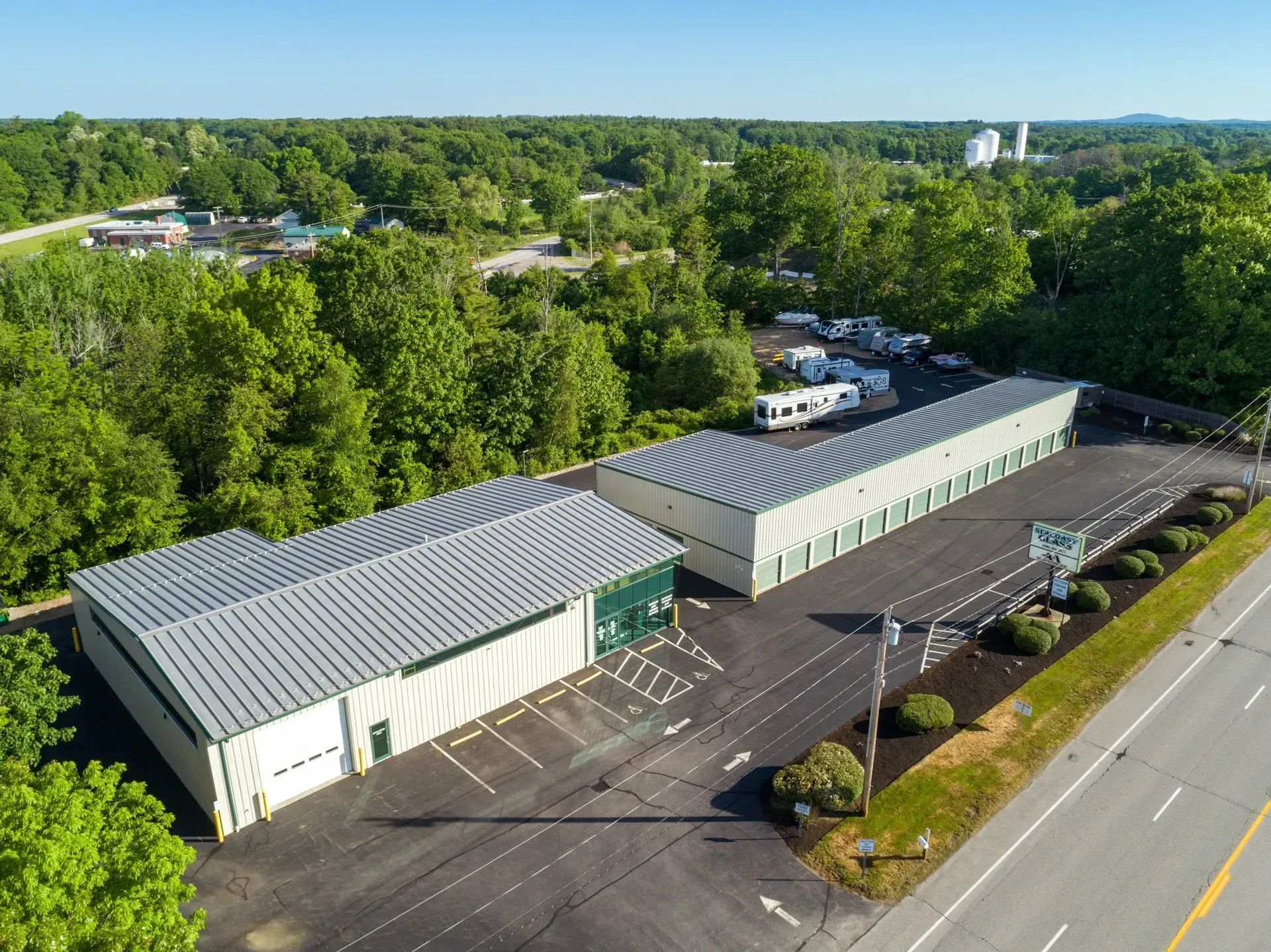 An aerial view of a storage facility surrounded by trees and a road.