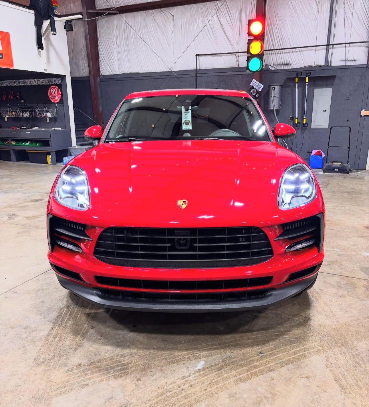 Red Porsche Macan SUV, facing forward, under a traffic light.