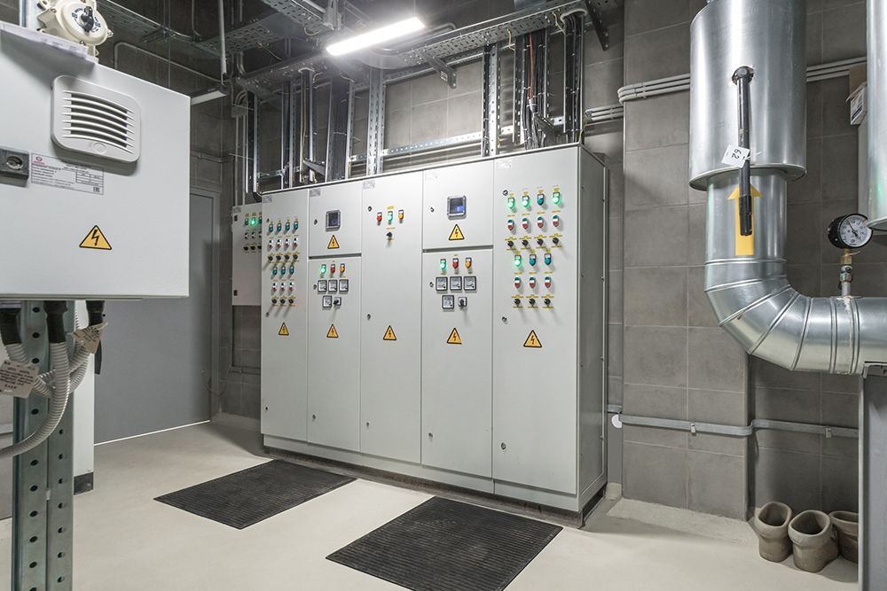 Electrical control panels in an industrial setting, grey with various switches, gauges, and warning symbols.