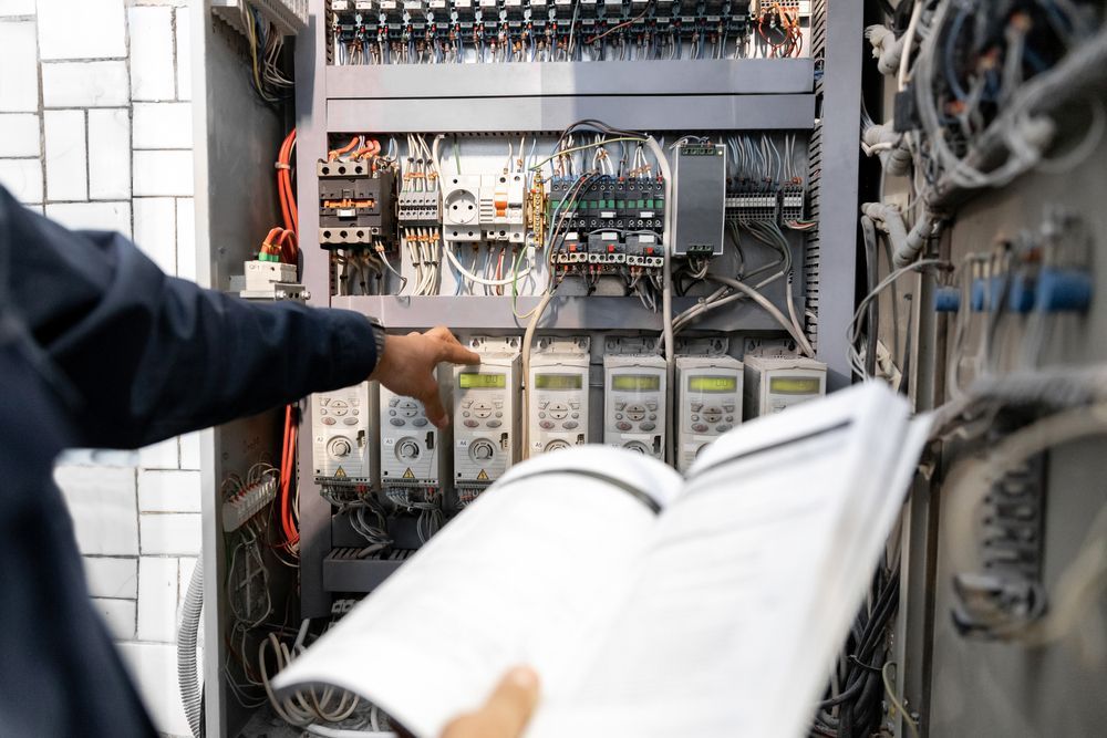 Technician reading manual while adjusting electrical panel components.