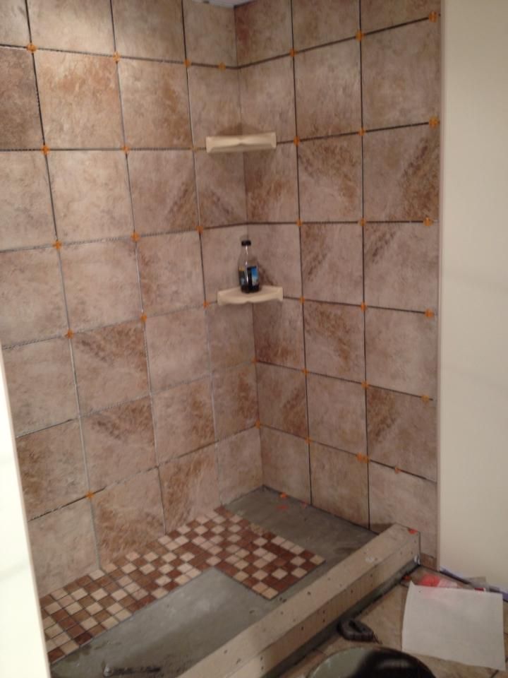 A bathroom with tiled walls and a shelf with a bottle on it