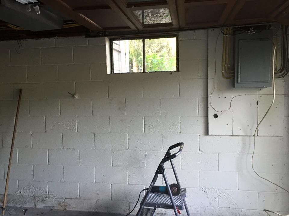 A ladder is sitting in a garage next to a window.