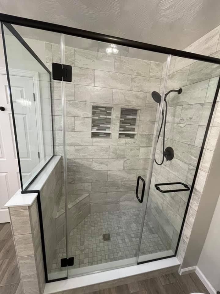 A bathroom with a walk in shower with a glass door.