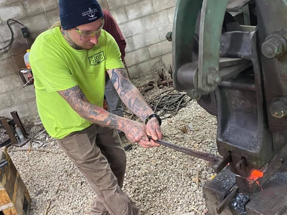 A man is using a machine to forge a piece of metal.