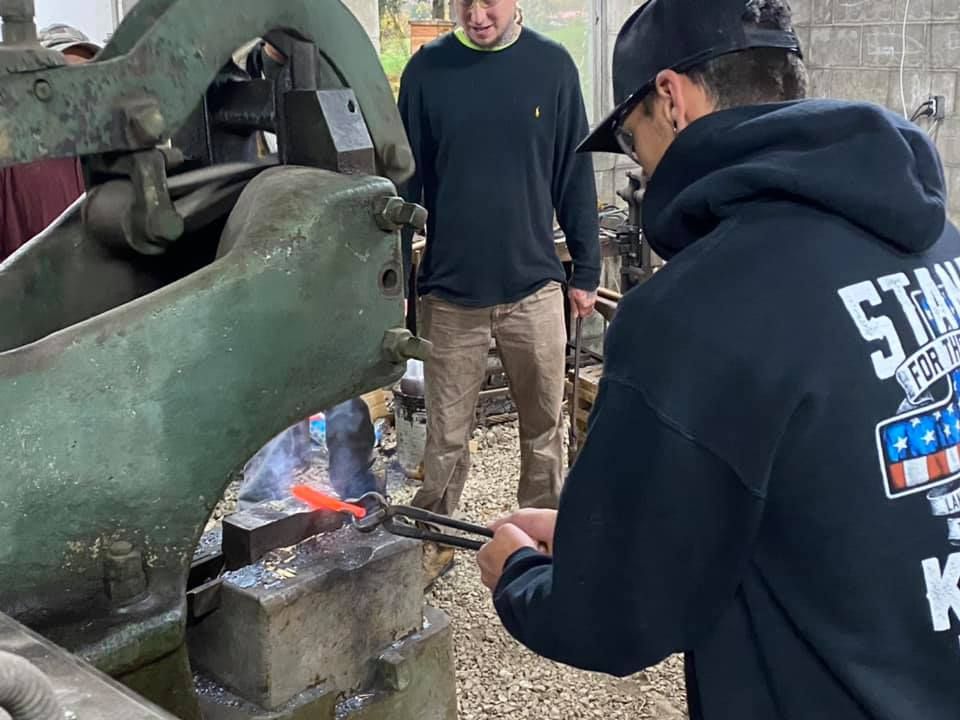 A man in a black hoodie is working on a machine.