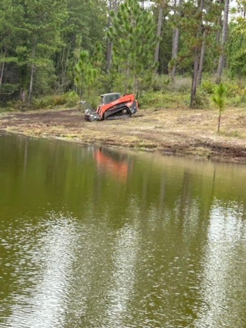 A tractor is parked on the shore of a lake.
