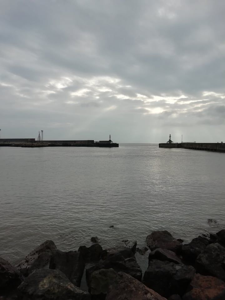 A distant view of the pier as the sun is shining down on the sea