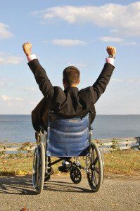 man in a wheelchair raising his arms