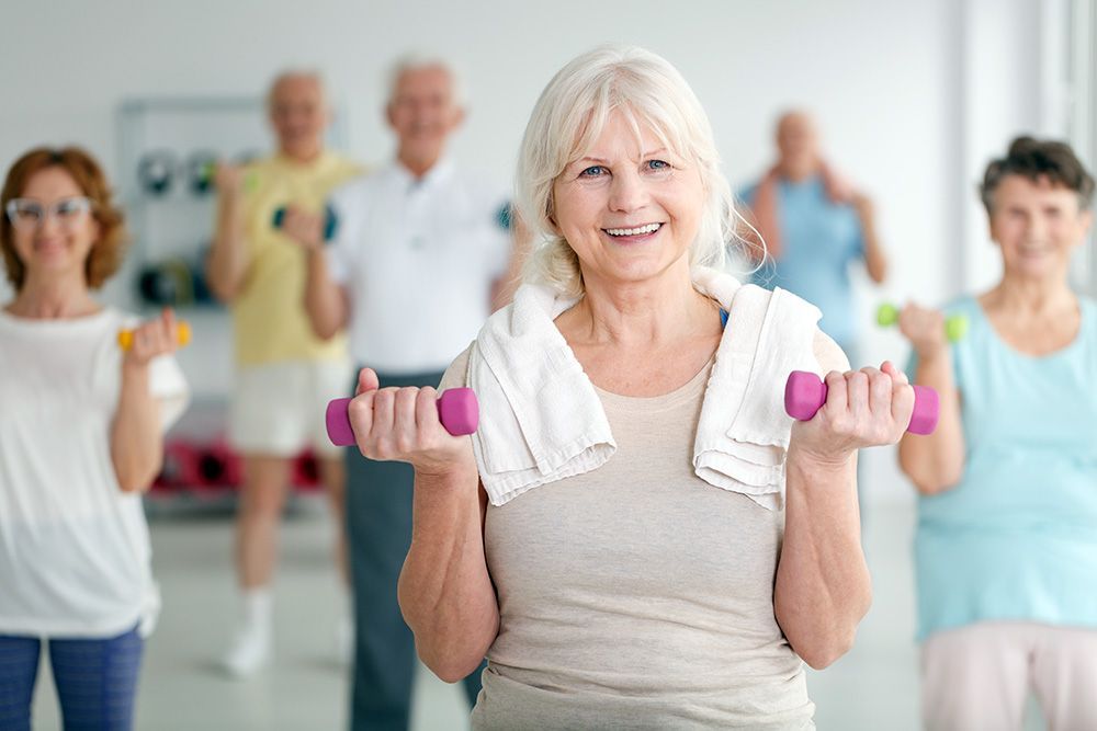 A group of elderly people are lifting dumbbells in a gym.