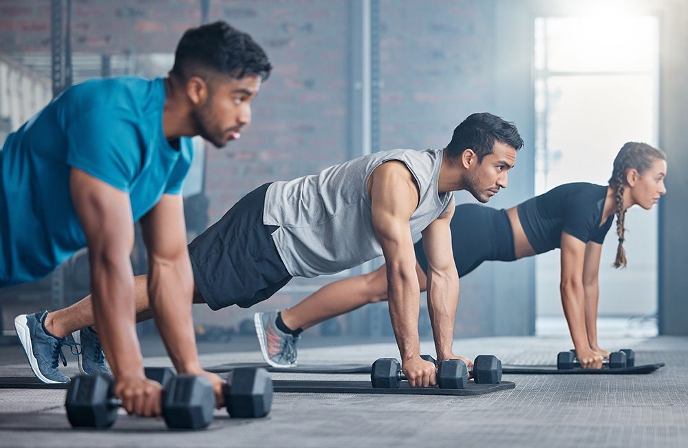 A group of people are lifting barbells in a gym.