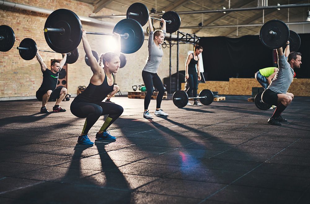 A group of people are lifting barbells in a gym.