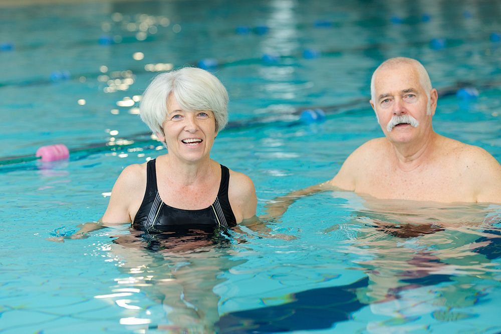 A man and a woman are swimming in a swimming pool.