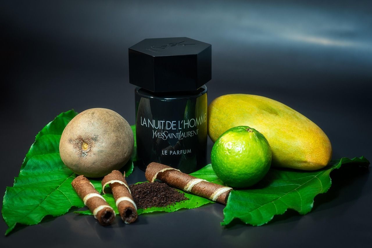 Zwarte parfumfles met kiwi, limoen, mango, wafels en bladeren op een donkere achtergrond.