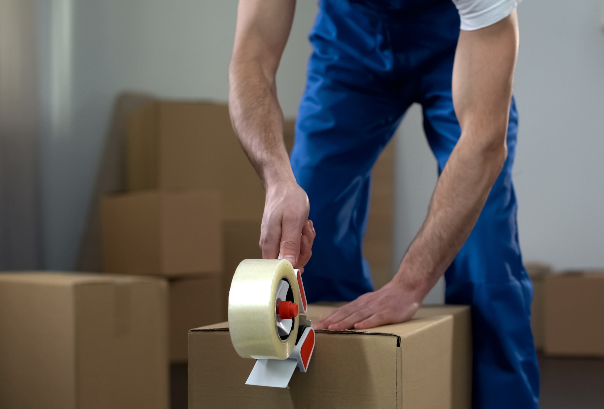 A man is taping a cardboard box with tape.