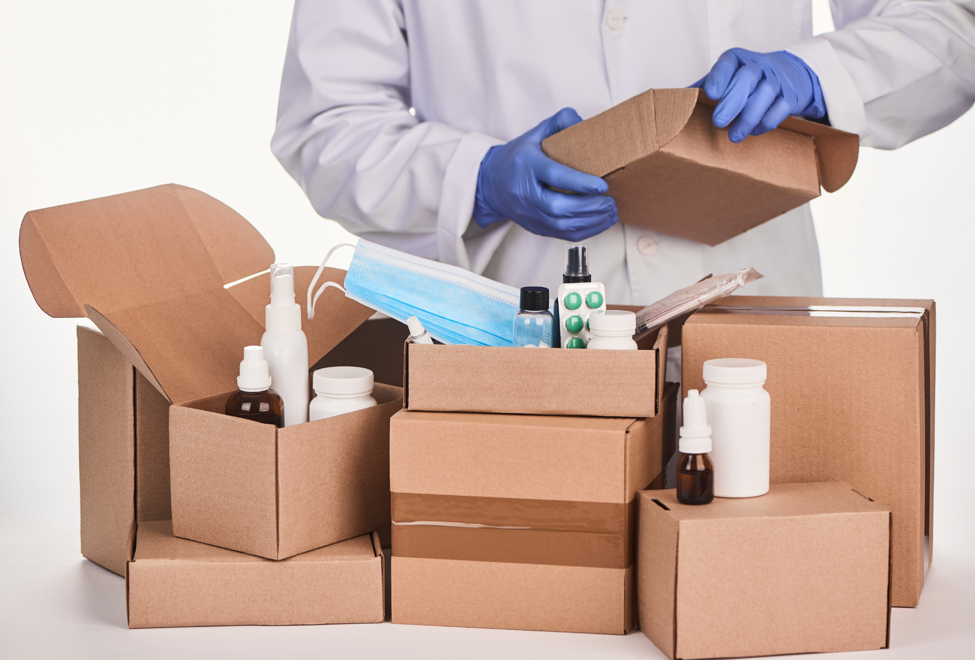 A doctor is opening a cardboard box filled with medical supplies.