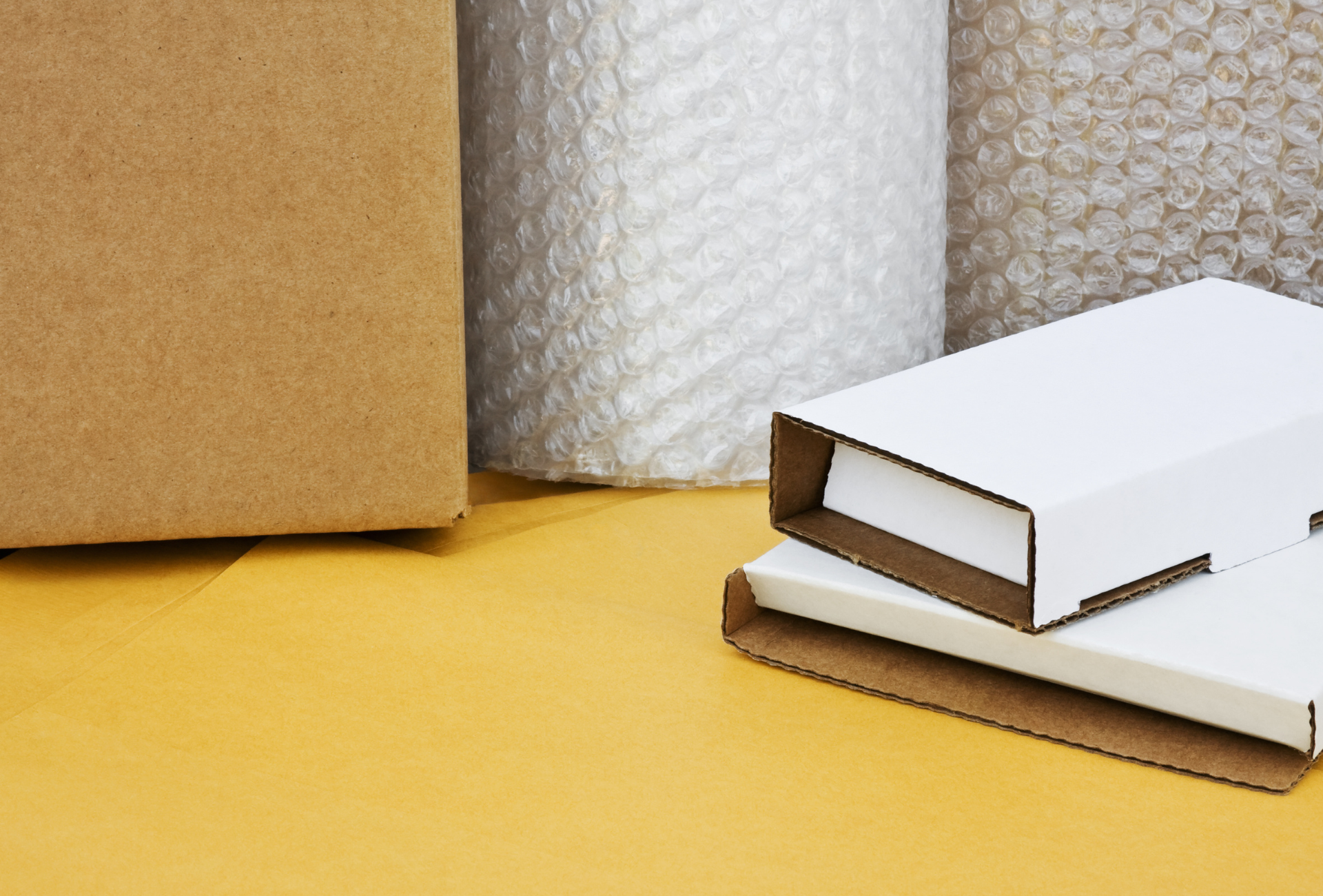 There are many different types of boxes and bubble wrap on the table.