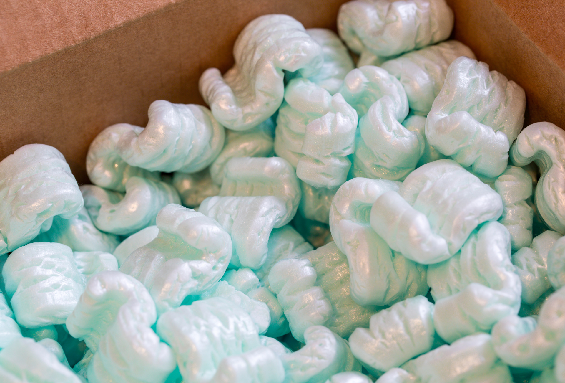 A pile of blue packing peanuts in a cardboard box.