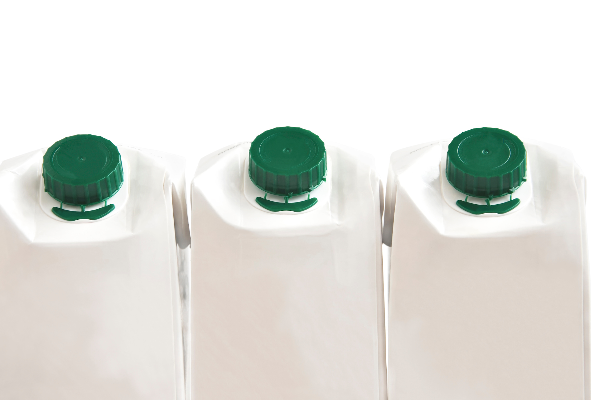 Three cartons of milk with green lids are lined up in a row.