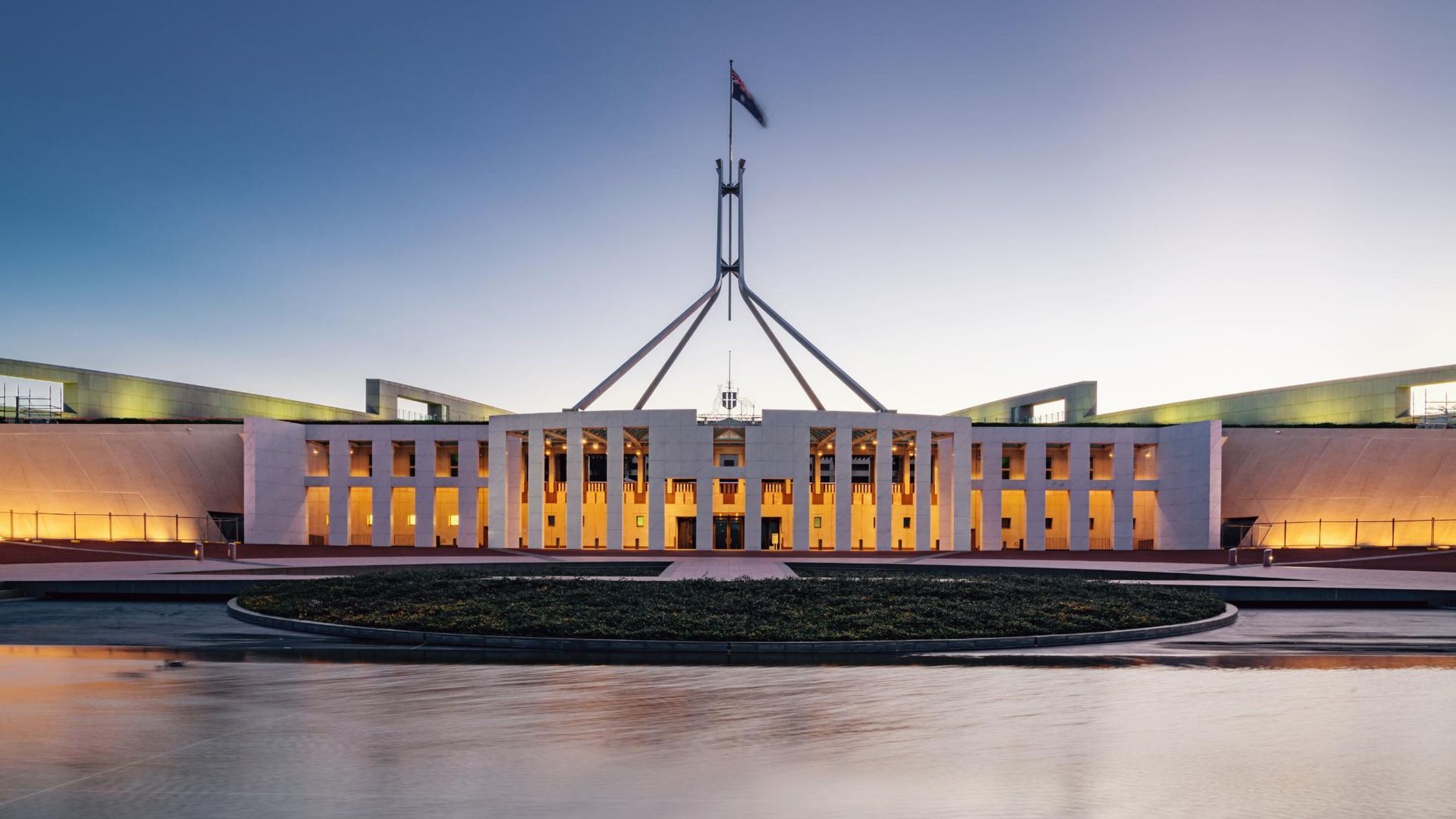 A Large Building With a Flag on Top of it is Sitting Next to a Body of Water