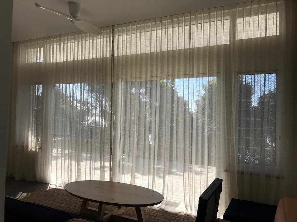Room With Soft, Sheer Curtains Diffusing Natural Light Through Large Windows