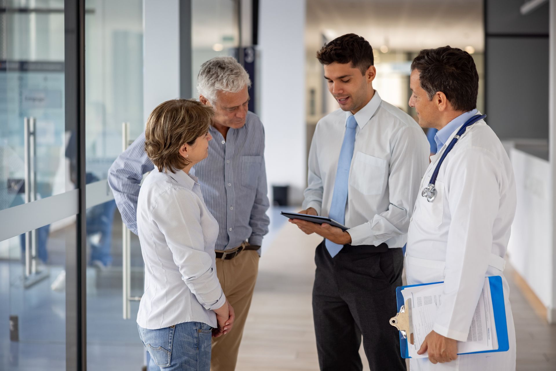 A group of people are standing in a hallway talking to a doctor.