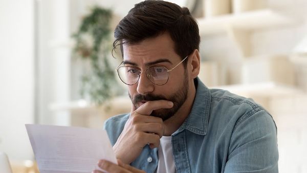 A man wearing glasses is looking at a piece of paper.