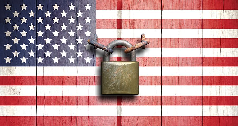 American flag with padlock and chain over wooden planks.